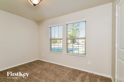 the living room of a home with a carpeted floor and three windows