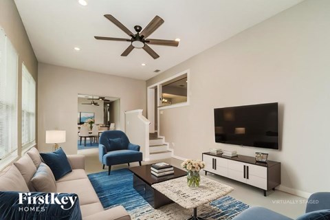 A living room with a blue rug and a television on the wall.