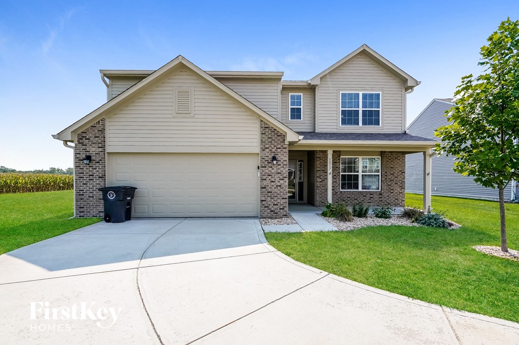 a beige house with a driveway in front of a lawn