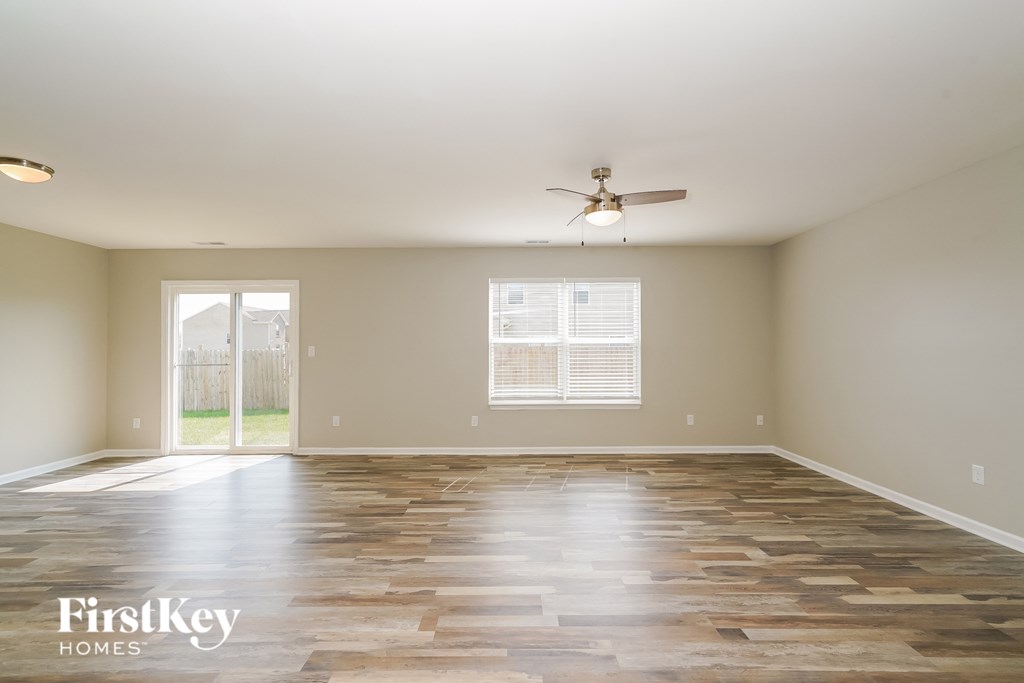 a empty living room with wood floors and a ceiling fan