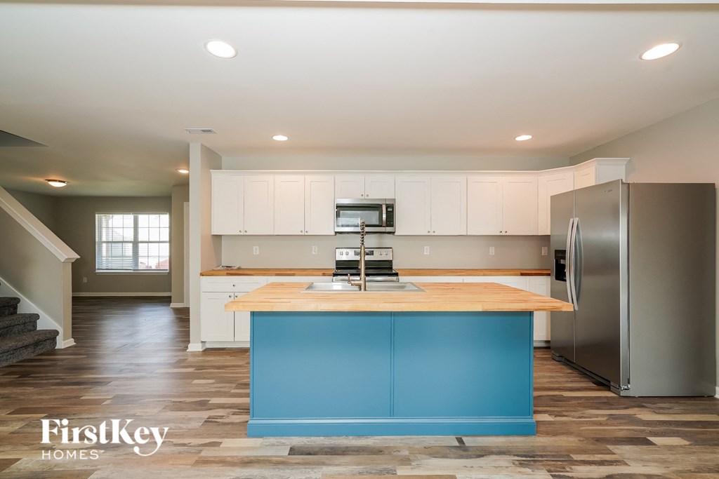 a kitchen with blue island and white cabinets and stainless steel appliances