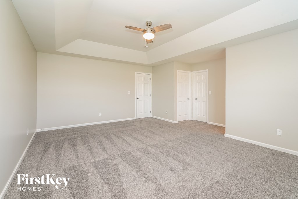 a spacious living room with carpet and a ceiling fan