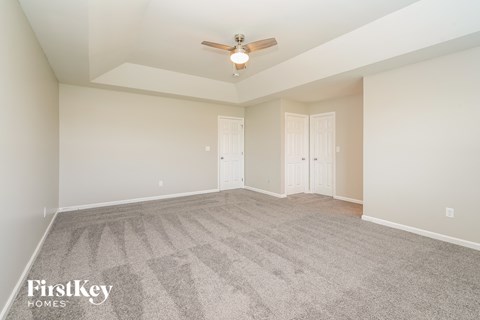 a spacious living room with carpet and a ceiling fan