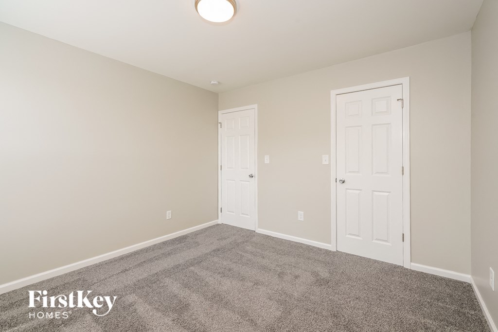 a bedroom with a carpeted floor and two closet doors