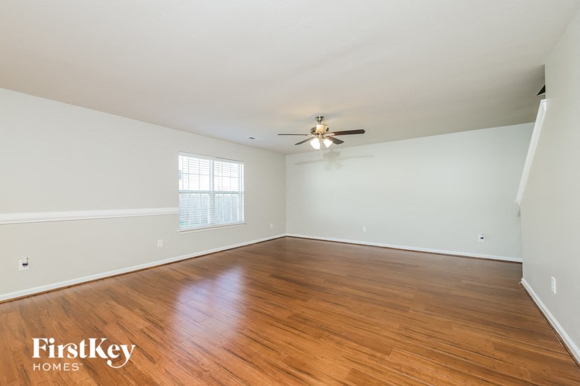 an empty living room with wood floors and a ceiling fan