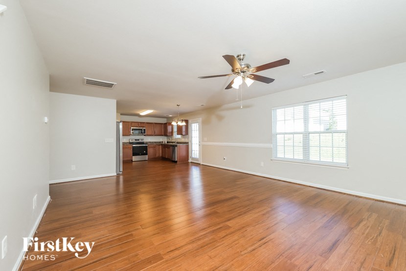 an empty living room with wood flooring and a ceiling fan