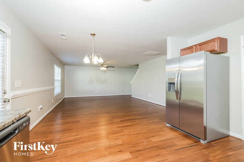 an empty kitchen and living room with a stainless steel refrigerator