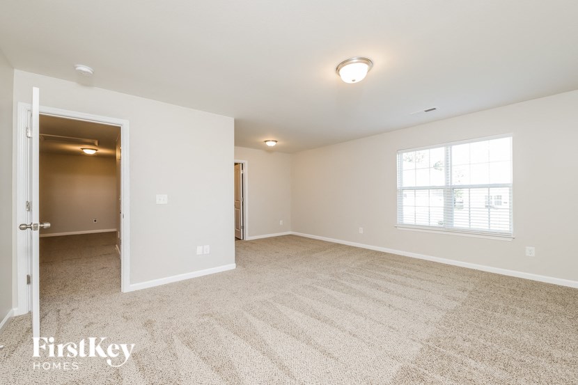 a spacious living room with carpet and a door to a bedroom