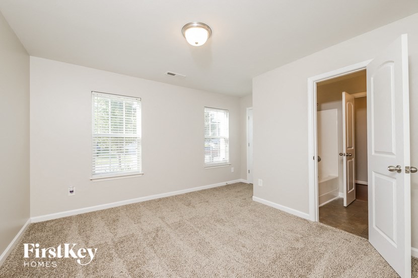 a bedroom with white walls and carpet and a door to a closet