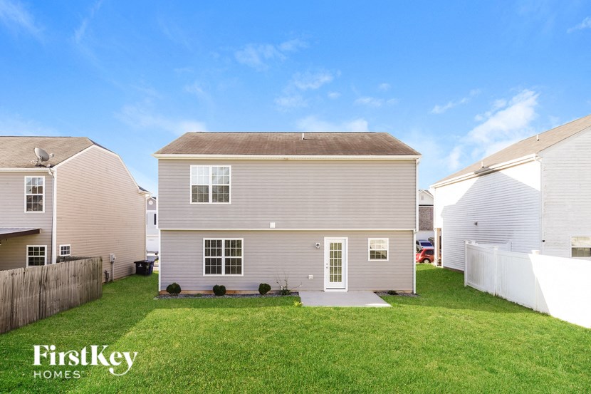a white house in a backyard with a green lawn