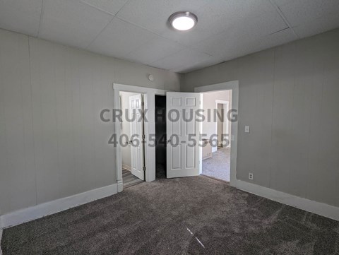 a small living room with a carpeted floor and two open doors