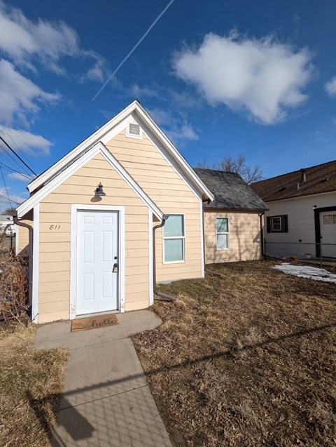 the front of a small yellow house with a white door