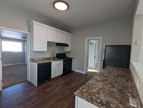 a kitchen with granite counter tops and black appliances and white cabinets