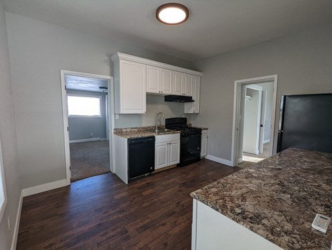 a kitchen with white cabinets and granite counter tops and a black stove