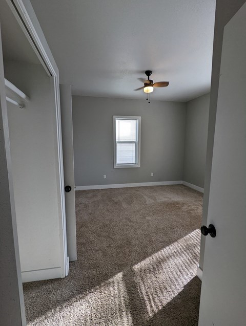 a bedroom with a carpeted floor and a ceiling fan