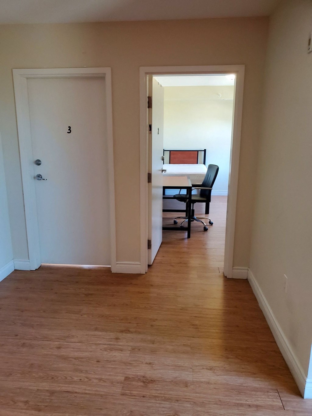a room with a desk and a chair in it and a hallway with a door
