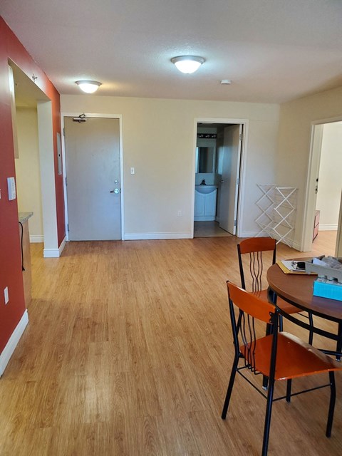 a kitchen and living room with a wooden floor and a table and chairs