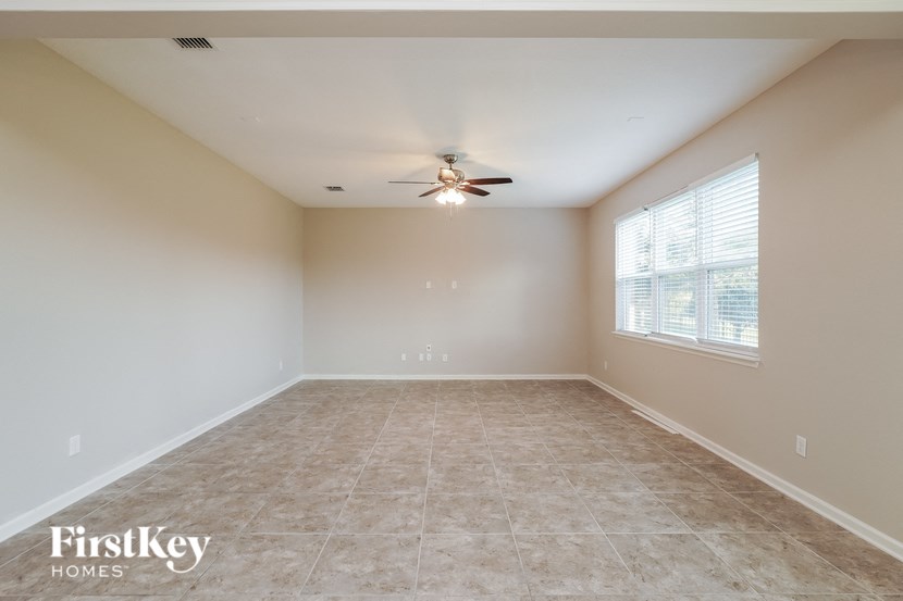 an empty living room with a ceiling fan and a window