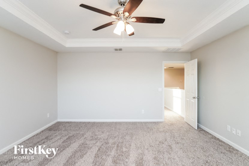 an empty living room with a ceiling fan and a white wall