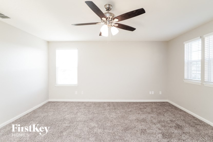 a living room with a ceiling fan and a carpet