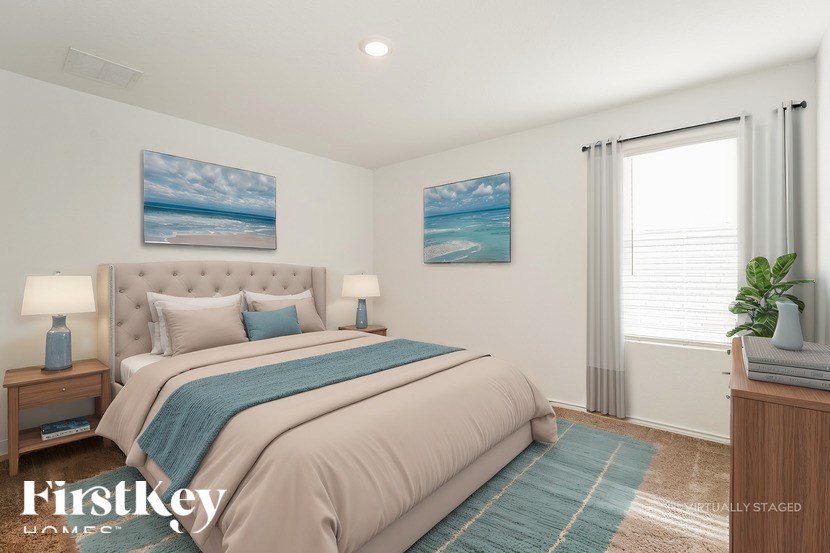 A bedroom with a large bed and a painting of a beach on the wall.