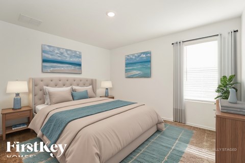 A bedroom with a large bed and a painting of a beach on the wall.