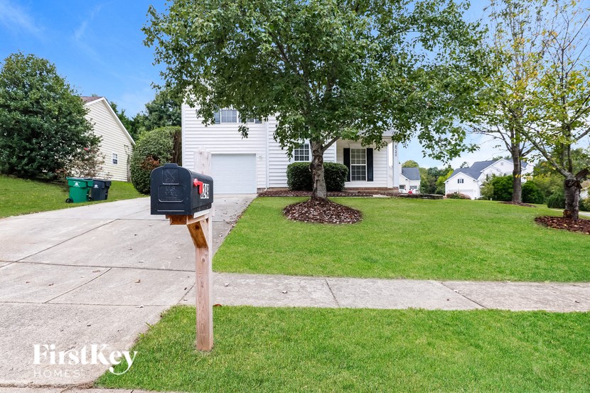 A white house with a black mailbox on a wooden post.