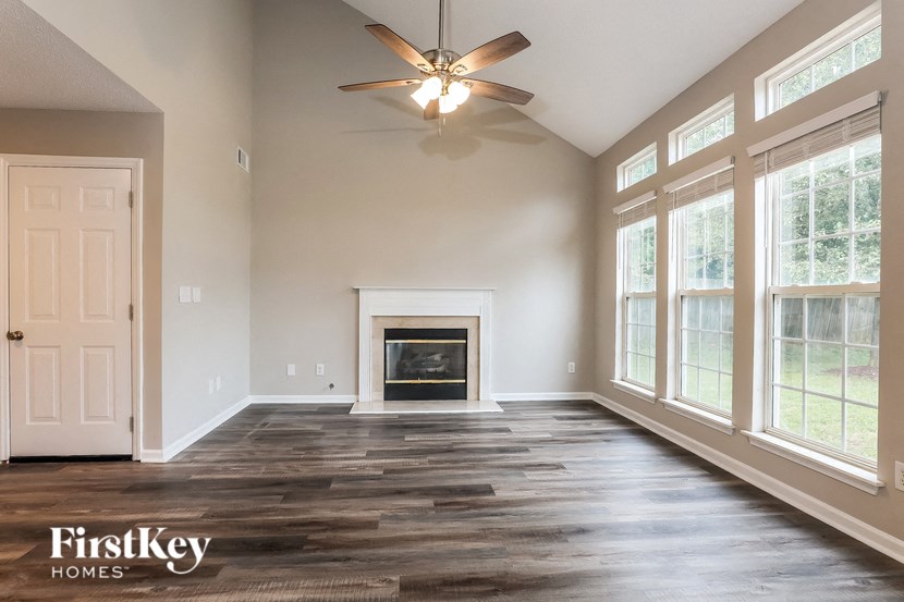 A spacious living room with a fireplace and a ceiling fan.
