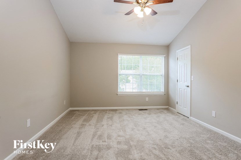 A room with a carpeted floor and a ceiling fan.