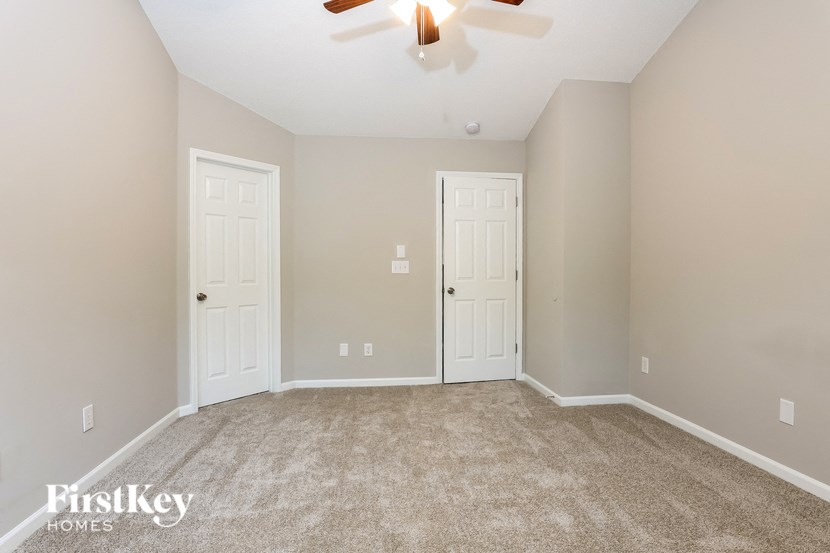 A room with a carpeted floor and two white doors.