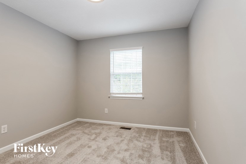 A room with a carpeted floor and a window with blinds.