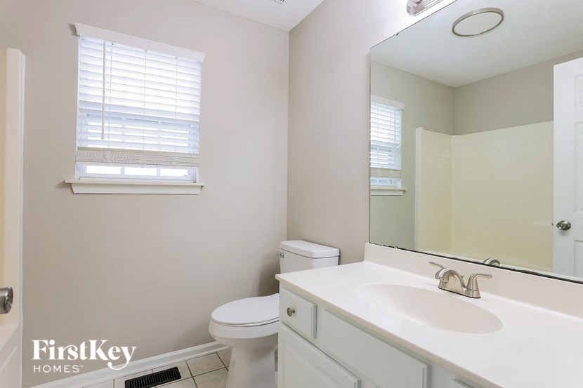 A bathroom with a toilet, sink, and mirror.