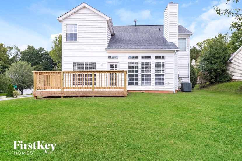 A white house with a wooden deck in front of it.