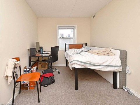 A bedroom with a bed, desk, chair, and a window.