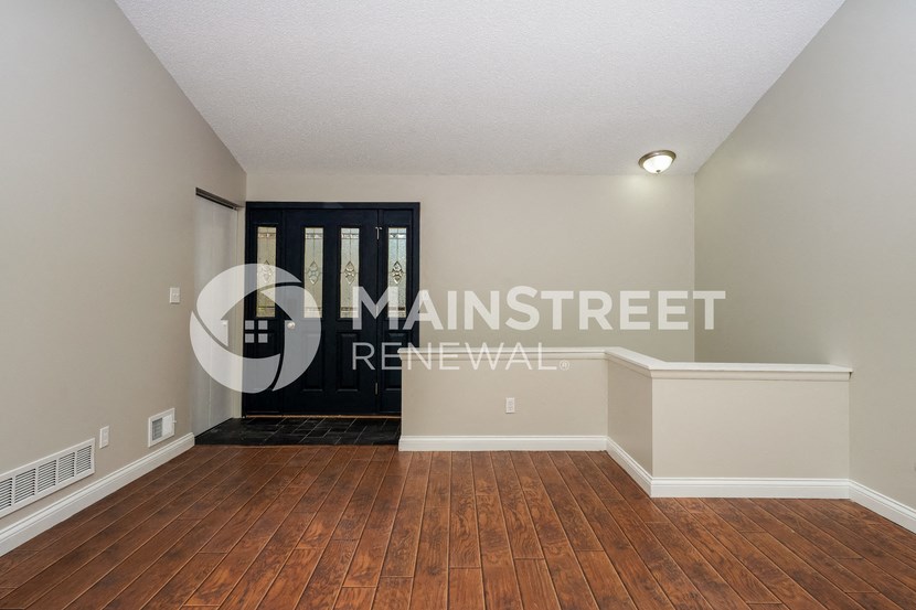 a living room with hardwood floors and a door to a hallway