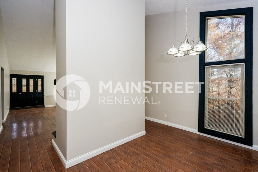 a renovated living room with a hardwood floor and large windows