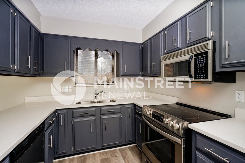 a kitchen with dark blue cabinets and white counter tops
