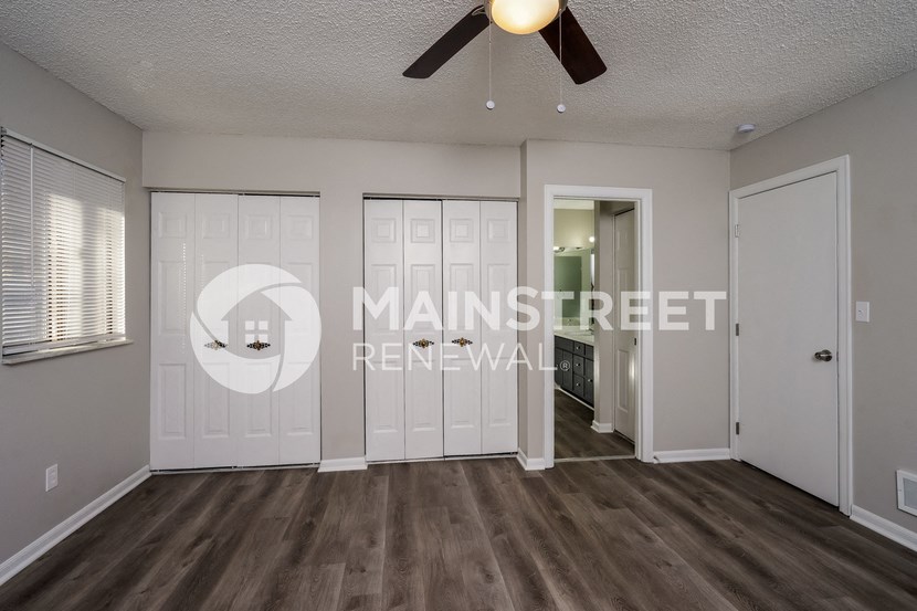 a living room with white doors and a ceiling fan