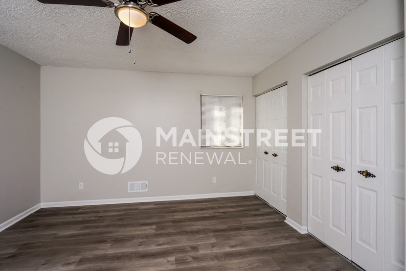 a living room with two closets and a ceiling fan