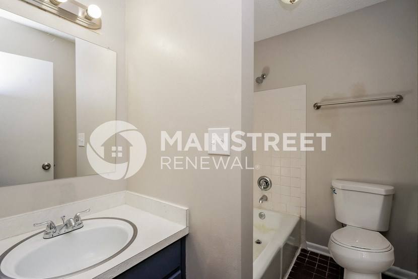 a renovated bathroom with a white sink and toilet and a tub