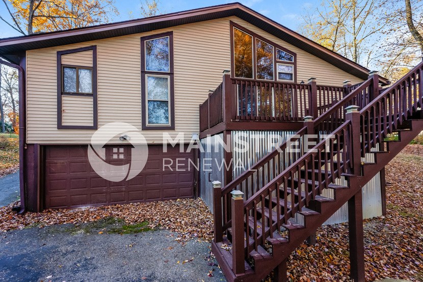 a home with a wooden staircase and a brown garage