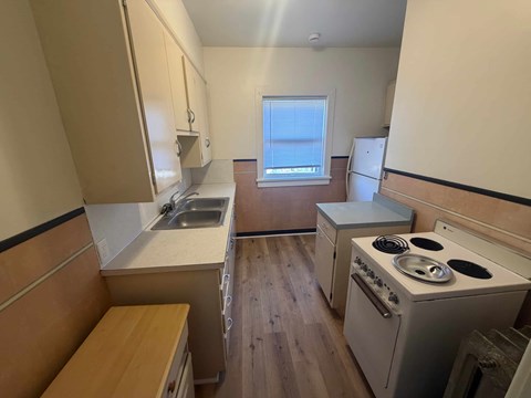 A small kitchen with a stove, sink, and window.