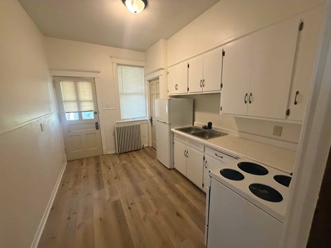 A kitchen with white cabinets and a stove top oven.