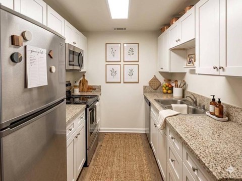 A kitchen with a refrigerator on the left and a sink on the right.