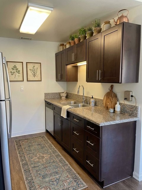 A kitchen with dark brown cabinets and a rug on the floor.