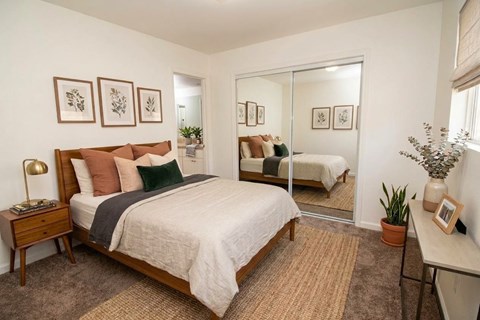 A bedroom with a bed, nightstand, and a mirror.