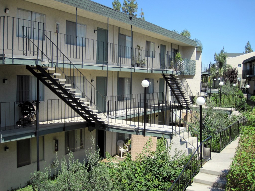the exterior of an apartment building with stairs and plants