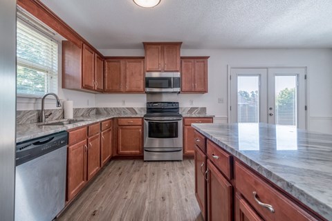 A kitchen with wooden cabinets and a marble countertop.