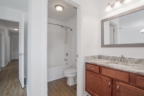 A bathroom with a white toilet and a wooden vanity.