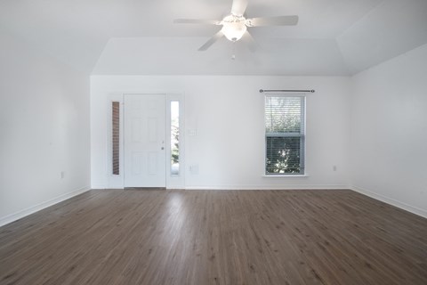 A room with a ceiling fan and a window with blinds.
